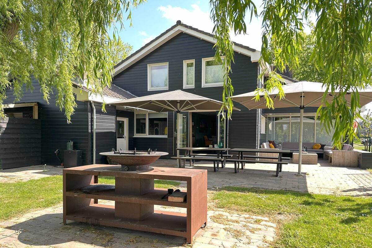 A patio area with a fire pit, outdoor seating, and umbrellas providing shade.