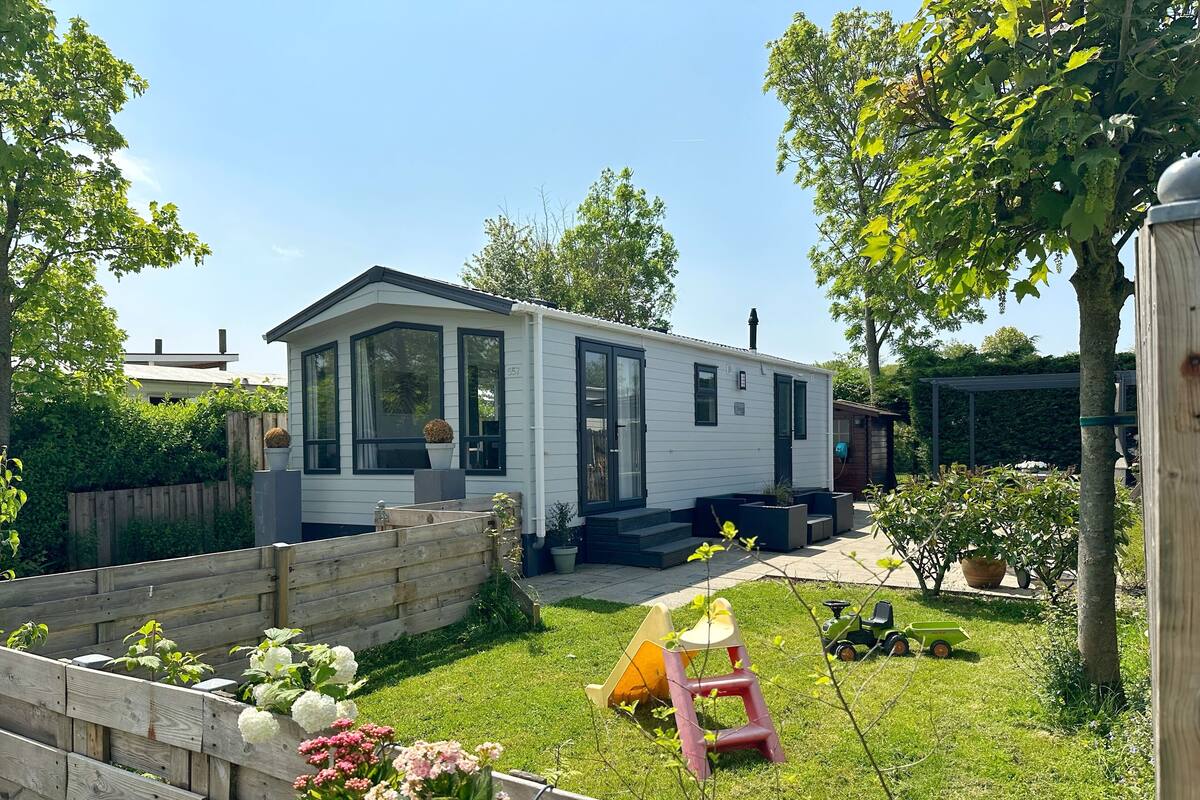 A mobile home with a fenced backyard, a small garden, and a patio area.