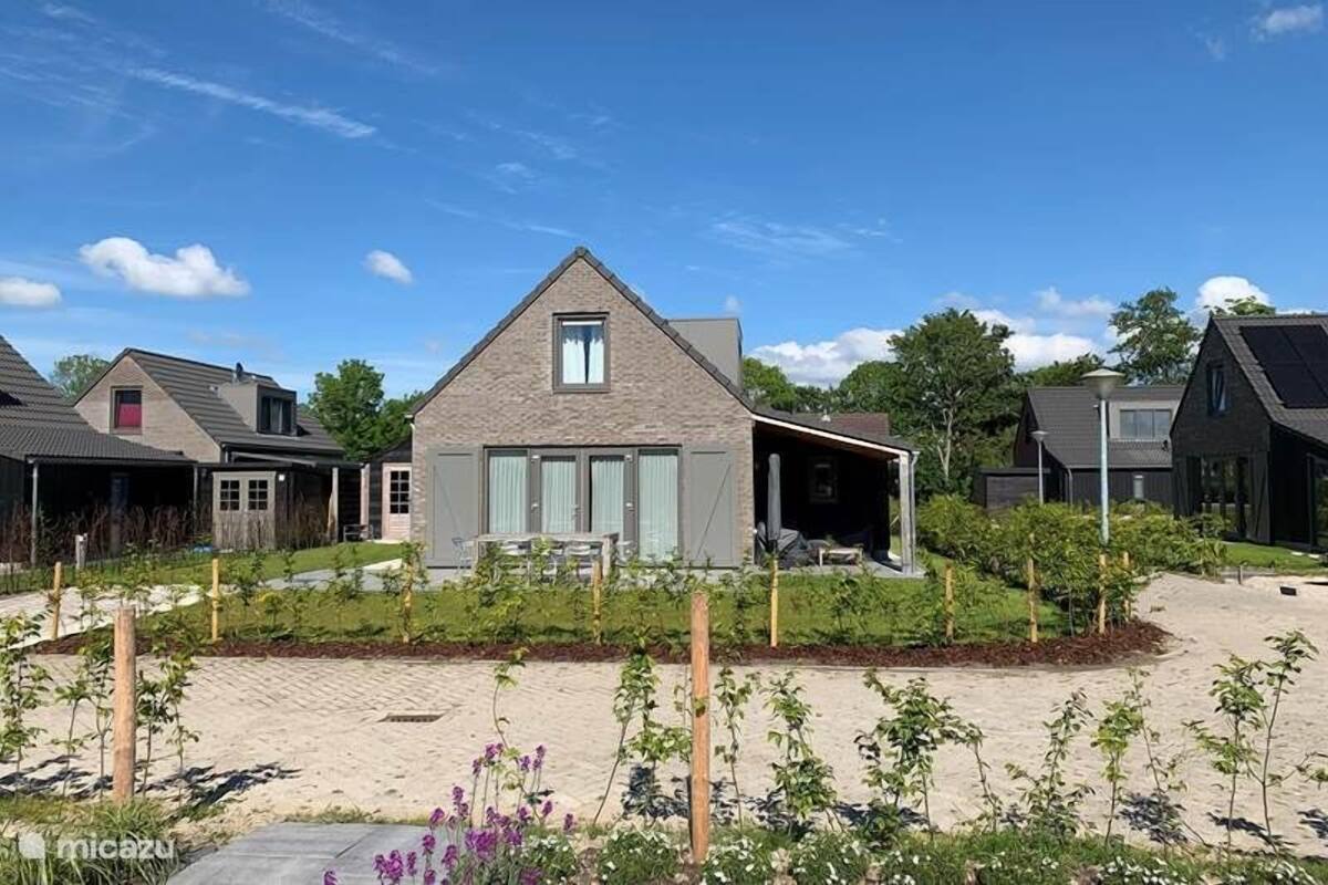 A modern house with a sloped roof, a covered porch, and a landscaped garden.