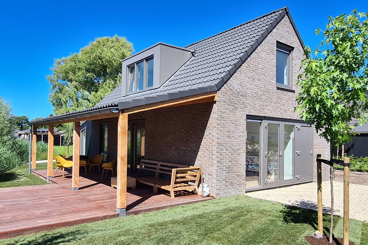 A modern house with a covered patio, a brick exterior, and a large sliding glass door.