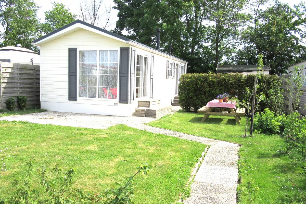 A single-story house with a front yard, a wooden deck, and a small garden area.