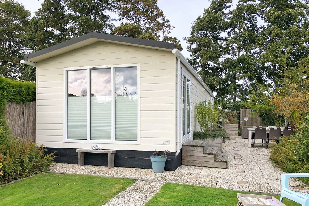 A mobile home with a patio area, a small garden, and a seating area with outdoor furniture.
