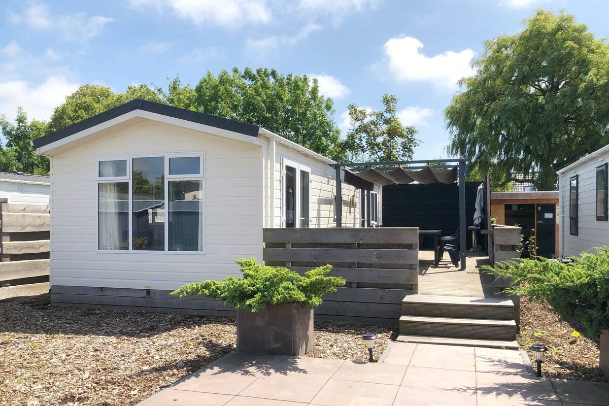 A mobile home with a patio area, a small deck, and a garden with potted plants.