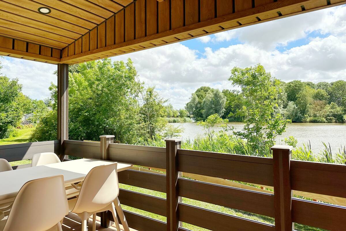 A covered outdoor seating area with a view of a lake and surrounding greenery.