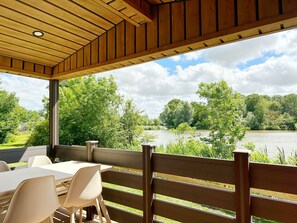 A covered outdoor seating area with a view of a lake and surrounding greenery. - Recreatiepark De Wielen (Sint Maarten)
