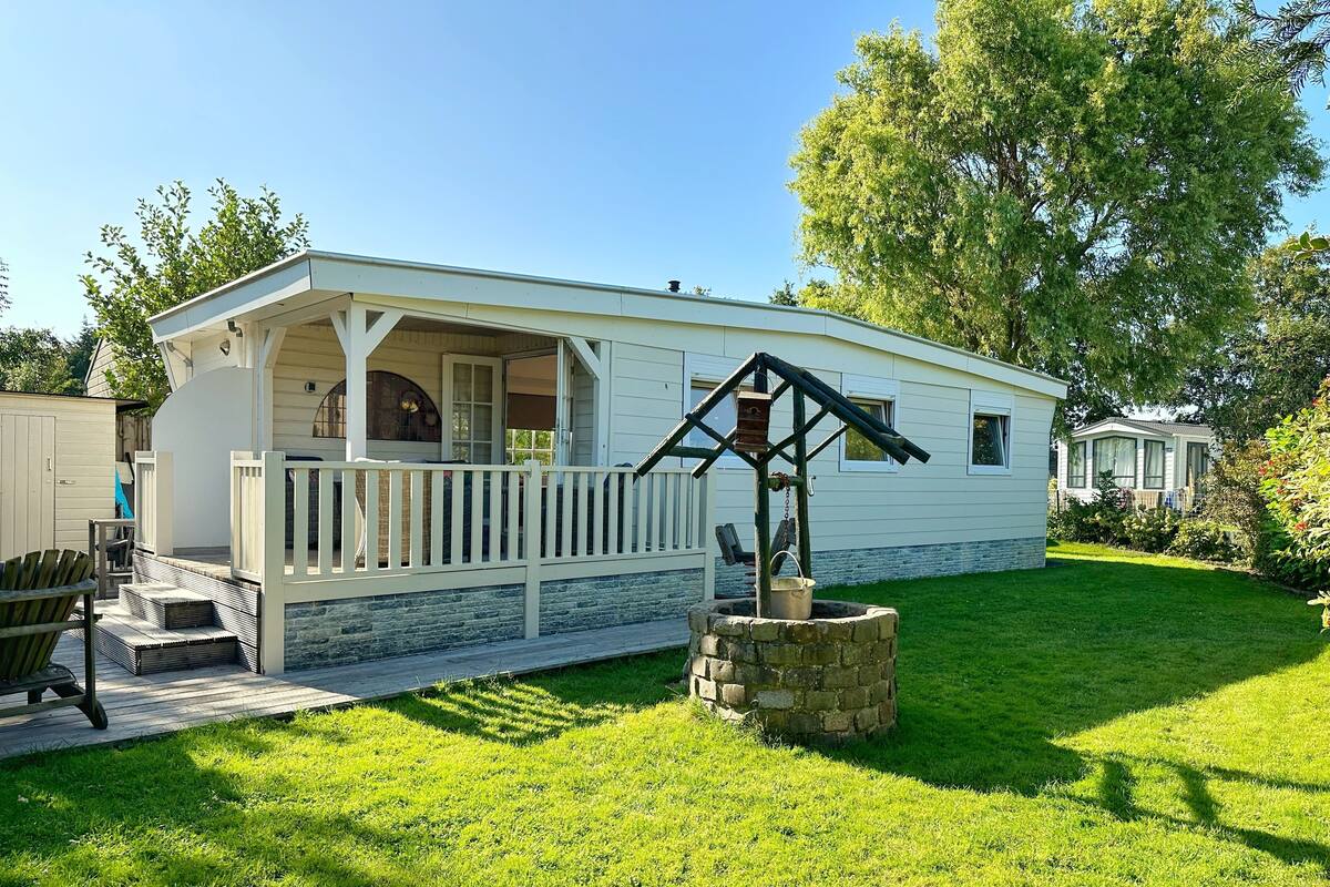 A white mobile home with a porch and a well-maintained lawn.