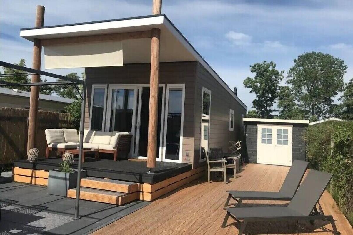 A modern house with a deck, outdoor furniture, and a small shed.