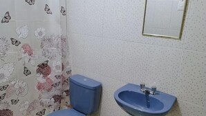 A bathroom with a toilet, sink, and shower curtain with floral and butterfly patterns. - Ukumary Gosth (Cusco)