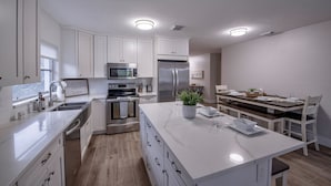Une cuisine moderne avec des meubles blancs, des appareils en acier inoxydable et un îlot central.