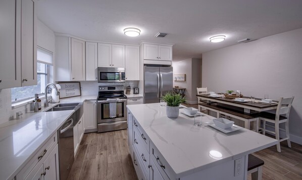 A modern kitchen with white cabinetry, stainless steel appliances, and a central island.