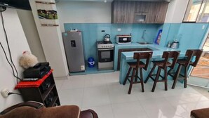 Un angolo cottura compatto con zona pranzo, frigorifero, forno a microonde e fornelli.