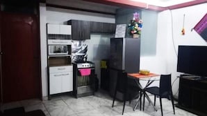 Una cucina compatta con zona pranzo, comprensiva di piano cottura, forno, frigorifero e un piccolo tavolo con sedie.