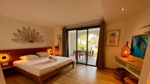 Ein Schlafzimmer mit Bett, Fernseher und einer Schiebetür zu einem Außenbereich.