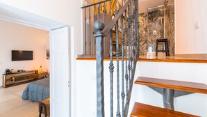 Un interior moderno con una escalera, un televisor de pantalla plana, un banco de madera y una cama.