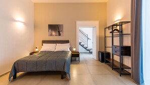 Un dormitorio moderno con una cama grande, lámparas de noche, una obra de arte en la pared y un armario empotrado.