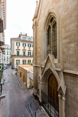 A cobblestone street with historic buildings, including a building with a large arched window and a door with intricate carvings. - Partenope at Residenza Partanna (Naples)
