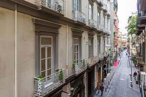 A narrow cobblestone street lined with multi-story buildings, featuring balconies with metal railings and some greenery. - Partenope at Residenza Partanna (Naples)