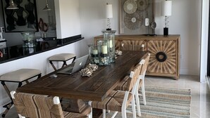 A dining area with a wooden table, woven chairs, and a chandelier. - Beautiful Key Largo Bayside Condo! (Key Largo)