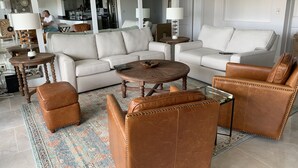 A spacious living room with a beige sofa, a brown leather armchair, and a coffee table. - Beautiful Key Largo Bayside Condo! (Key Largo)