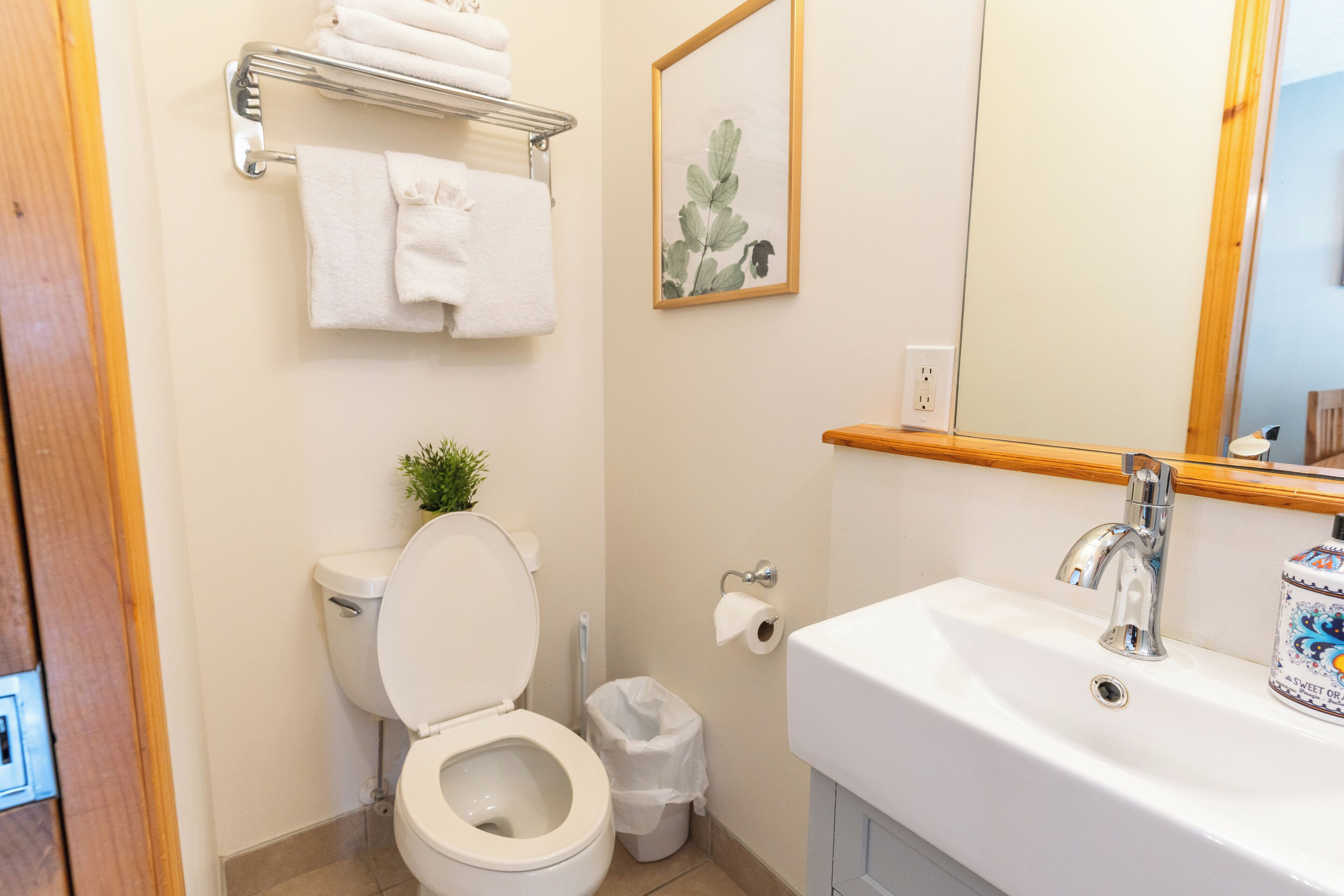A bathroom with a toilet, sink, and a small trash bin.