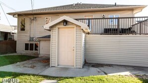 Ein eingeschossiges Haus mit Garage, einem kleinen Anbau und einem umzäunten Deck.