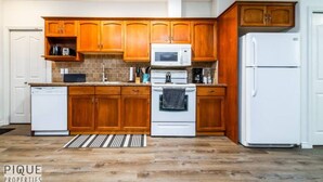 Eine Küche mit Holzausstattung, einem weißen Kühlschrank, einer Mikrowelle und einem Geschirrspüler.