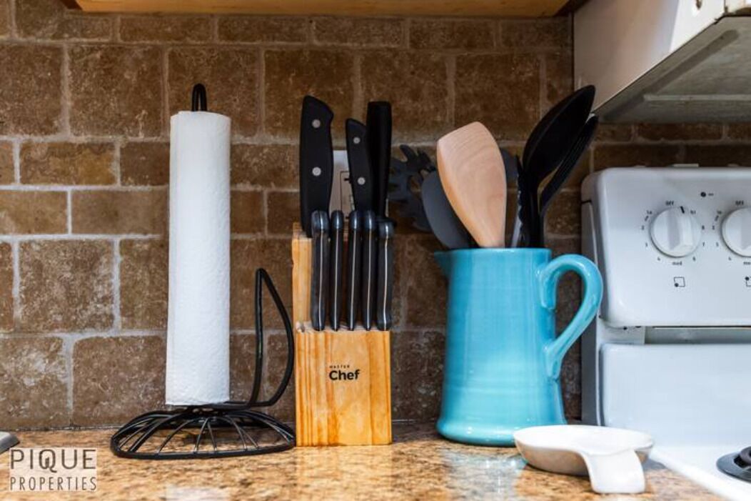 A kitchen counter with a roll of paper towels, a knife block labeled 'Chef', and a blue mug.