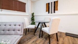 Ein Essbereich mit einem runden Tisch, vier Stühlen und einem gepolsterten Sofa.