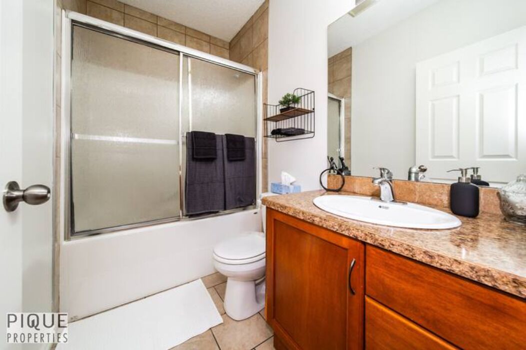 A bathroom with a shower, toilet, and vanity with a sink and mirror.