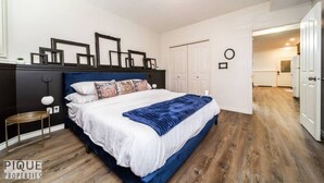 Un dormitorio con cama, mesita de noche, armario y puerta que da a otra habitación.