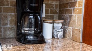 Eine schwarze Kaffeemaschine auf einer Granitarbeitsplatte mit einer Steinwand.