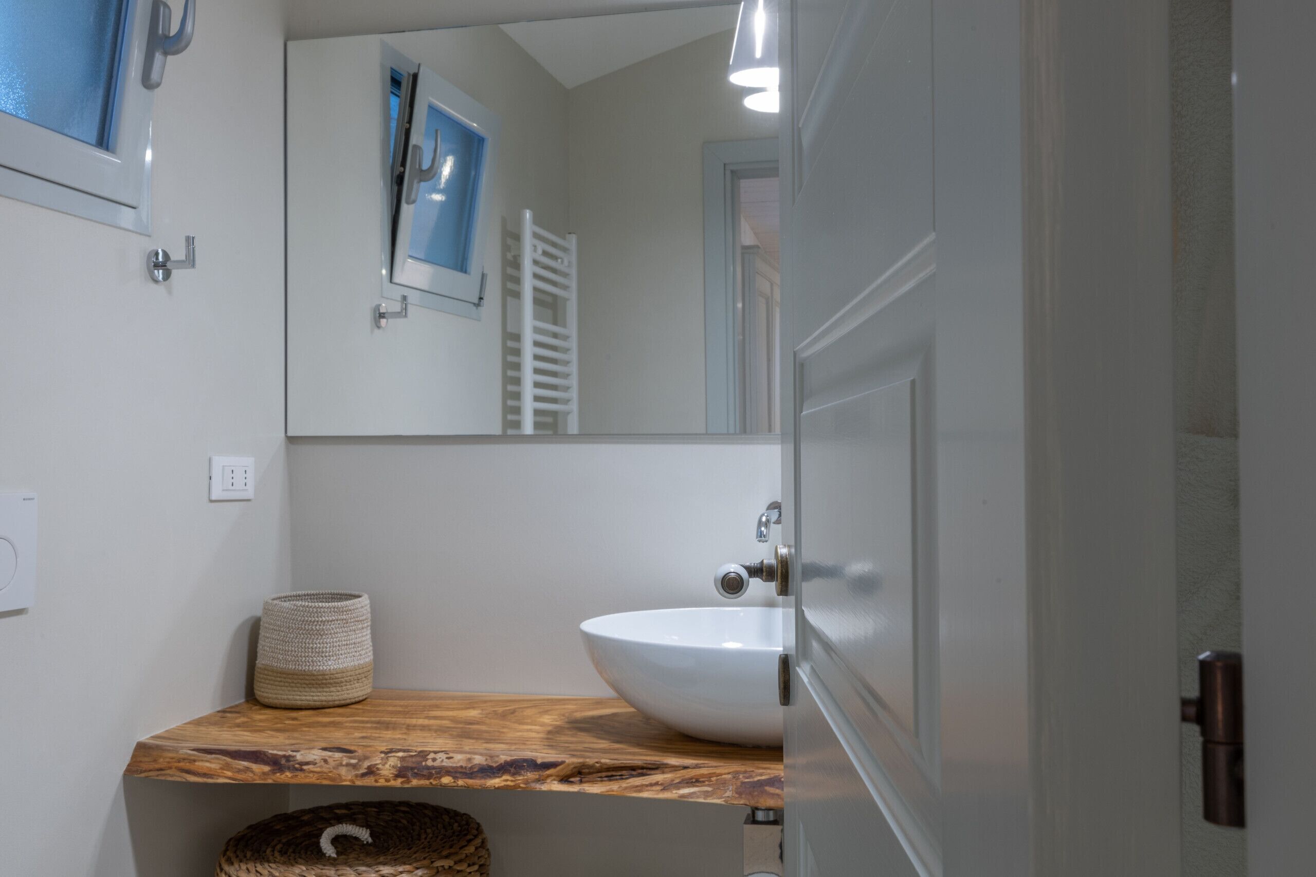 Un baño con tocador de madera, un lavabo blanco, un espejo y un perchero para toallas.