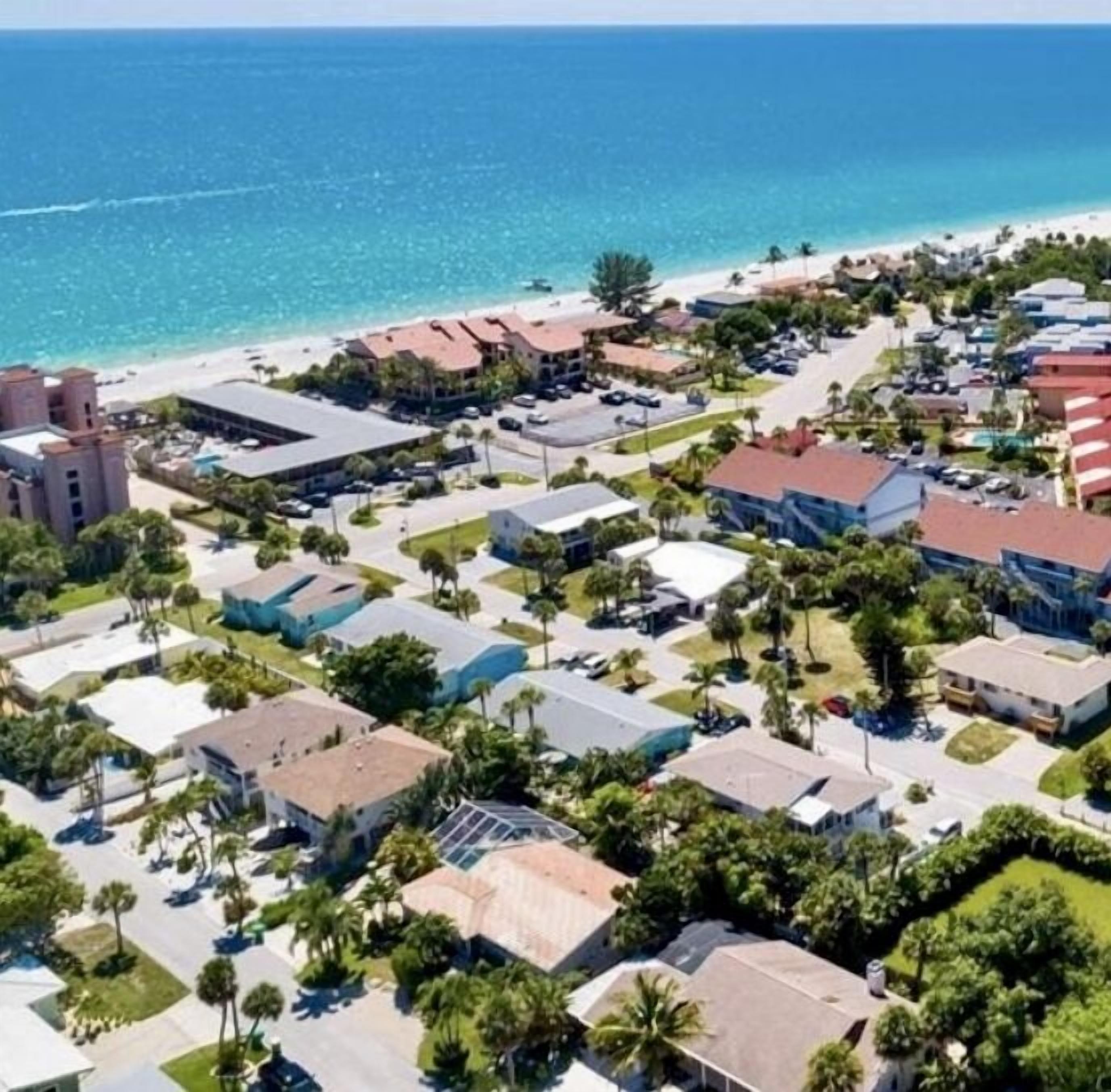 Zona turística costera con propiedades frente a la playa, un puerto deportivo y diversos edificios, incluyendo hoteles y posiblemente viviendas.