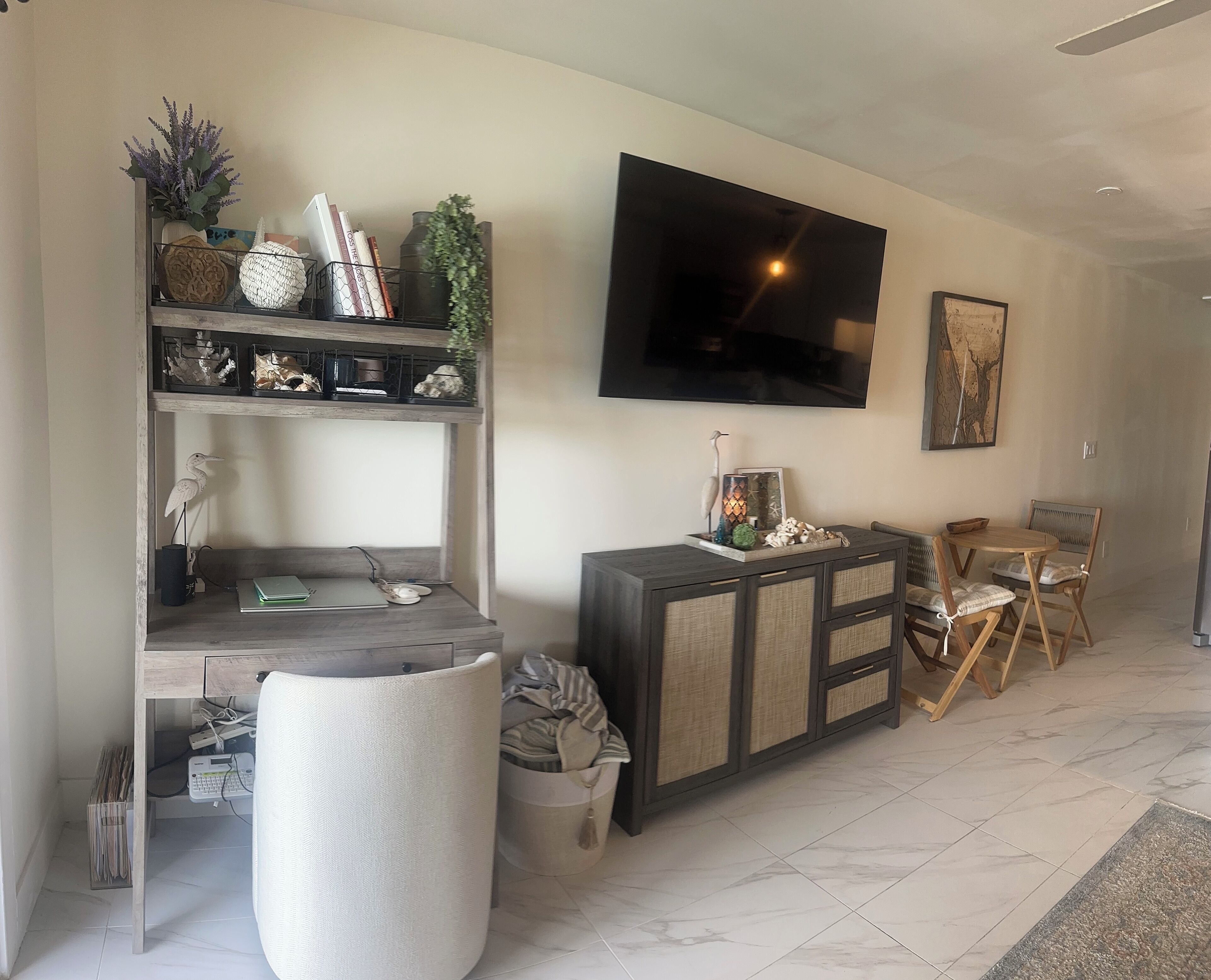 Una sala de estar moderna con televisor de pantalla plana, un comedor con sillas de madera y una estantería con objetos decorativos.