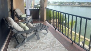 Un balcon donnant sur une rivière, une chaise, une table et un tapis à motifs.