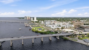 Un paisaje urbano costero con un puente destacado, edificios frente al mar y un puerto deportivo.
