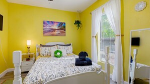 Un dormitorio con cama, mesita de noche, lámpara y ventana con cortinas.