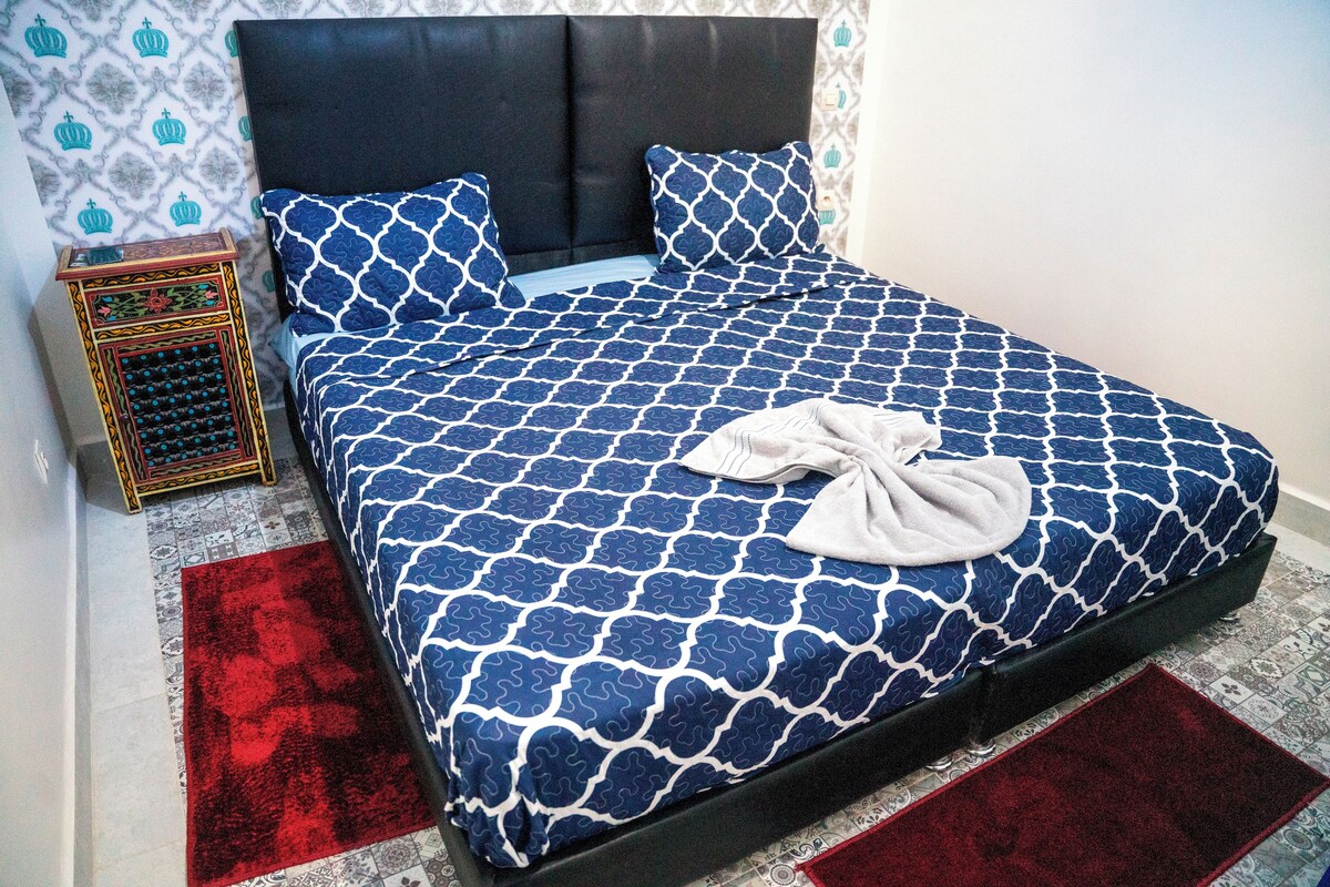 A bed with a patterned bedspread, a headboard, and two pillows.