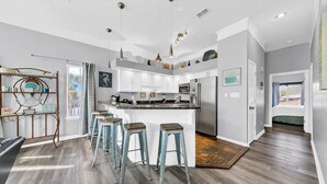 A modern kitchen with a central island, bar stools, and a dining area with a view. - ⭐Beach Across the Street-Pool+Hot Tub-The Palms A6⭐ (Panama City Beach)