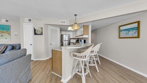 A compact kitchen with a central island, white cabinetry, and a hanging pendant light.