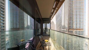A balcony with a glass railing, a table with chairs, and a vase of flowers. - Tranquil 2BR Haven in Heart Dubai Marina (Dubai)