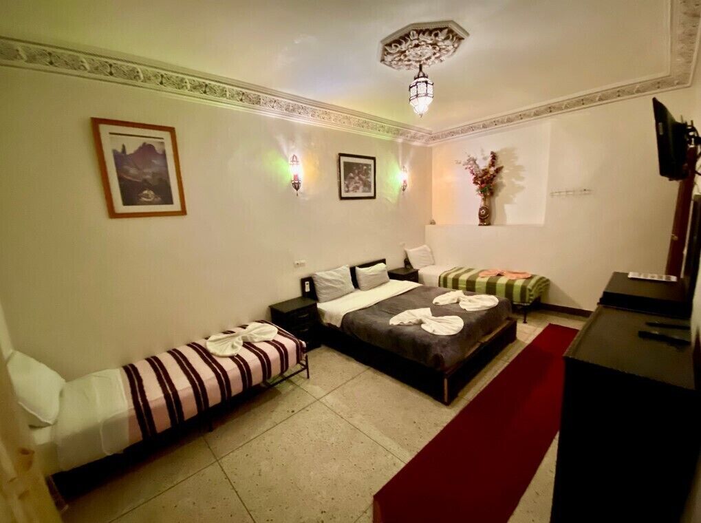 A hotel room with a large bed, a smaller bed, a desk, and a red carpet.