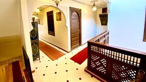 A hallway with a tiled floor, a wooden staircase, and a decorative railing. - Riad Jibril (Marrakech)