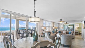 A spacious living area with a large dining table, comfortable seating, and a view of the ocean. - 2BR Penthouse with Panoramic Views + Private Beaches | Magnolia House 602 (Destin)
