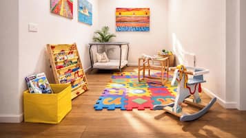 Ein Kinderzimmer mit Puzzlematt, Spielpferd, Bücherregal und Pflanze.