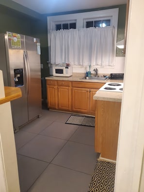 A kitchen with a refrigerator, microwave, sink, and stove.