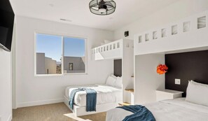 A modern bedroom with bunk beds, a large window, and a view of the outside.