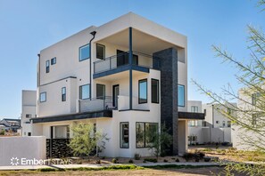 Un edificio moderno de dos pisos con balcones, ventanas amplias y techo plano.