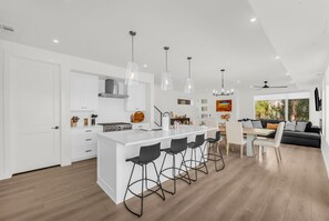 A modern kitchen with a central island, bar stools, and pendant lighting. - Desert Chic at Desert Color by Ember Stays (St. George)