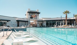 Relax by the pool surrounded by comfortable lounge chairs and umbrellas, with a unique tower in the background.